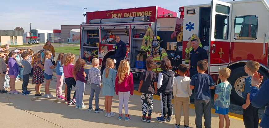 Fire truck, fire fighters, row of students in front of fire truck