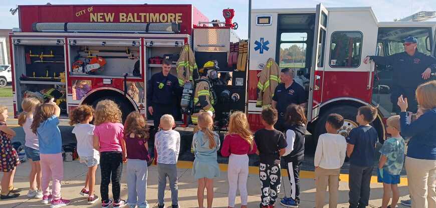 Fire truck, fire fighters, row of students in front of fire truck